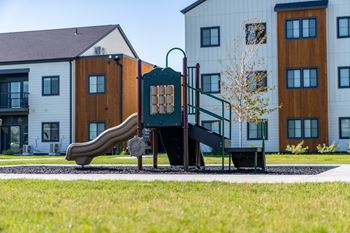 A playground with a slide and a bench in front of a building. at Silverbrook Apartments, Kalispell, MT, 59901