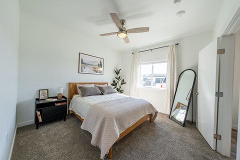 A bedroom with a bed, nightstand, and a ceiling fan. at Silverbrook Apartments, Montana, 59901