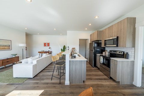 A modern kitchen with a white sofa and wooden cabinets. at Silverbrook Apartments, Kalispell, Montana