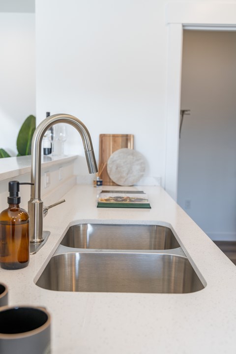 A kitchen sink with a silver faucet and a brown bottle on the counter. at Silverbrook Apartments, Montana, 59901
