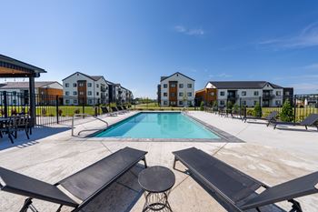 A swimming pool surrounded by lounge chairs and buildings in the background. at Silverbrook Apartments, Montana, 59901