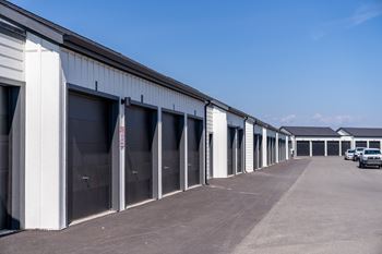 A parking lot with a white building and a car parked in front. at Silverbrook Apartments, Kalispell
