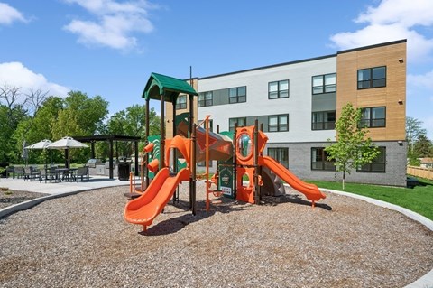 A playground with a red slide and a green roof.