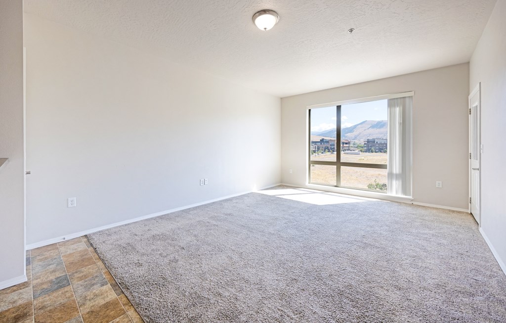 A spacious room with a large rug and a view of the outdoors through a sliding glass door. at Ashlyn Place, Missoula, MT, 59801