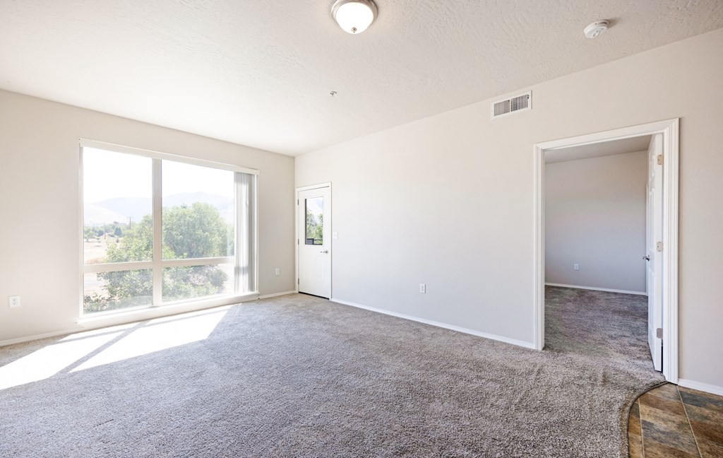 A spacious room with a carpeted floor and sliding glass doors leading to a balcony. at Ashlyn Place, Missoula