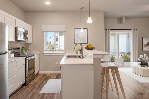 an open kitchen and dining area with a white counter top and a stainless steel refrigerator at Southside Townhomes, Idaho, 83686