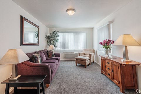 A living room with a couch, chairs, and a table with a vase of flowers.