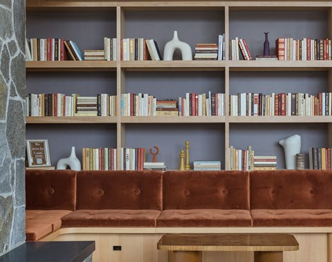 a brown couch sitting in front of a book shelf