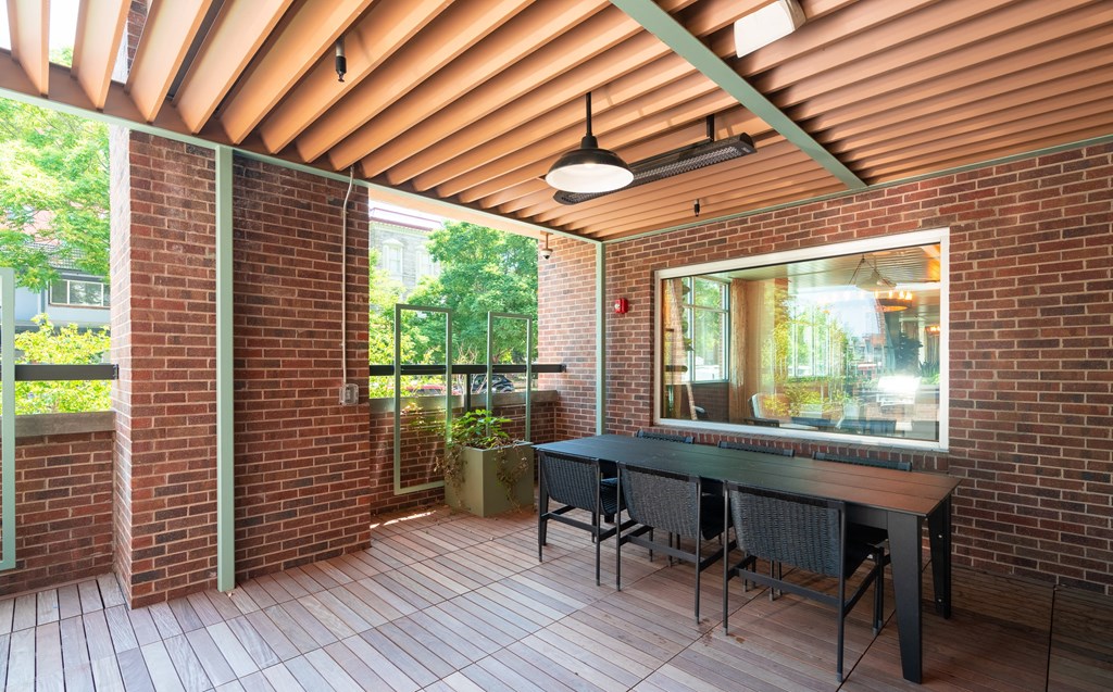 Covered red brick patio with hardwood flooring, a long table and chairs at Sylvan Uptown, Denver, CO, 80203