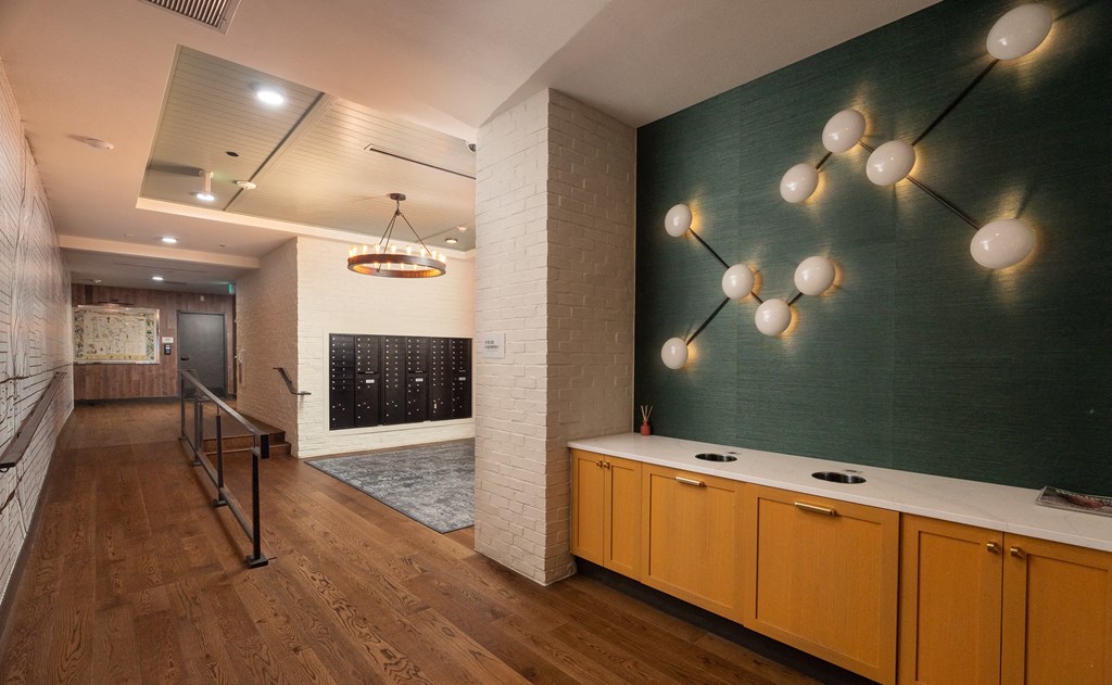 Spacious walkway to the mail area with chic wall decorations on the green wall and modern style chandelier at Sylvan Uptown, Colorado