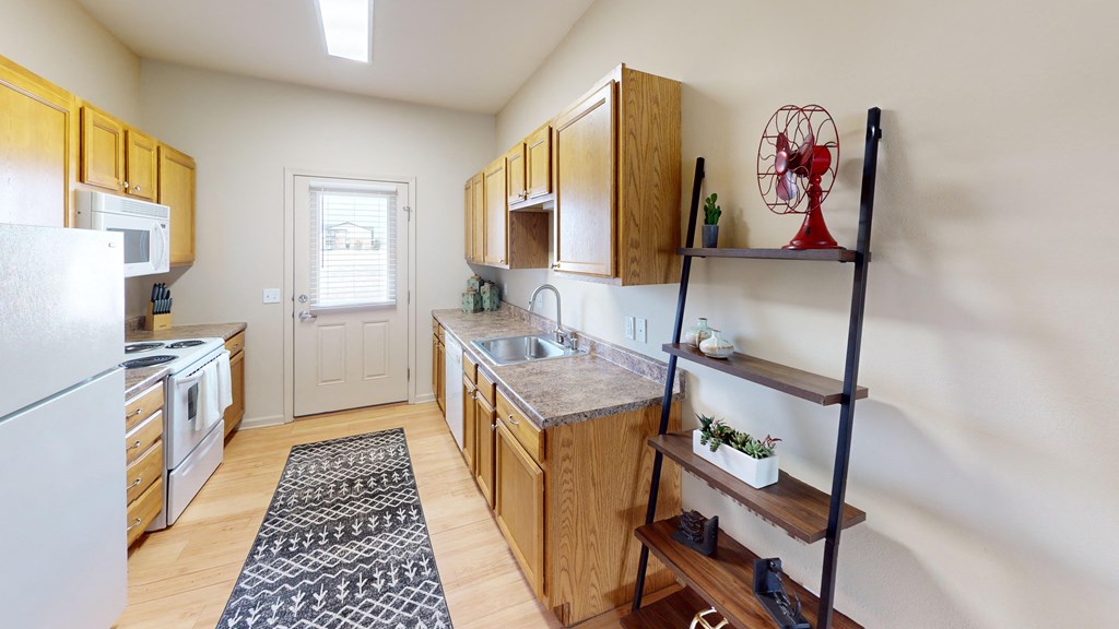 a kitchen with wooden cabinets and white appliances and a rug