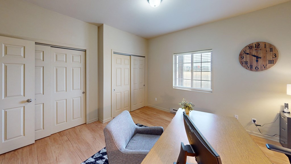 a living room with a desk and a clock on the wall