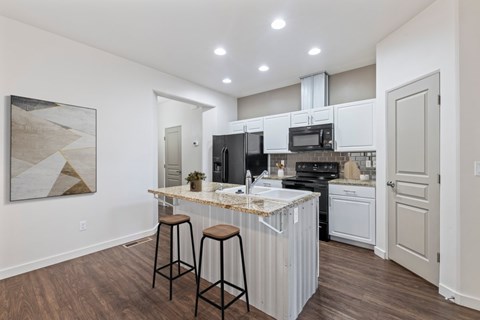 A kitchen with white cabinets and a marble countertop.