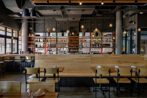 a restaurant with a bar and wooden tables and chairs at The Lucy Boise Apartments, Boise, ID
