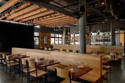 a restaurant with wooden tables and chairs and a bar at The Lucy Boise Apartments, Boise