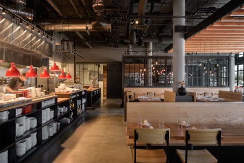 the interior of a restaurant with wooden tables and chairs and a bar with a counter at The Lucy Boise Apartments, Boise, Idaho