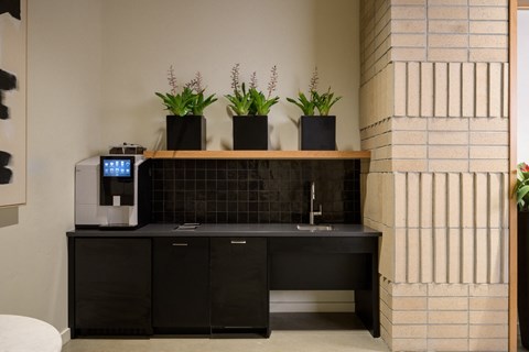 a lobby with a black counter with a coffee machine and plants at The Lucy Boise Apartments, Idaho