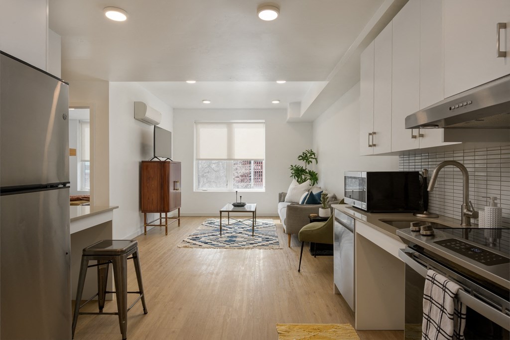 an open kitchen and living room with a large window and a refrigerator an open kitchen and living room with a large window and a refrigerator at The Lucy Boise Apartments, Boise