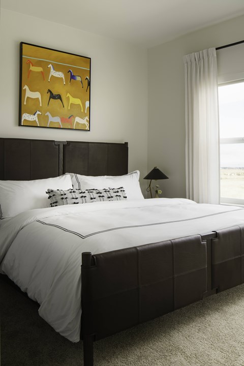A bedroom with a large bed and a painting of animals above it.