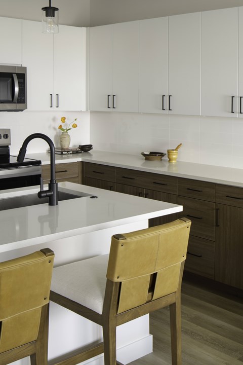 A kitchen with a white counter top and two chairs.
