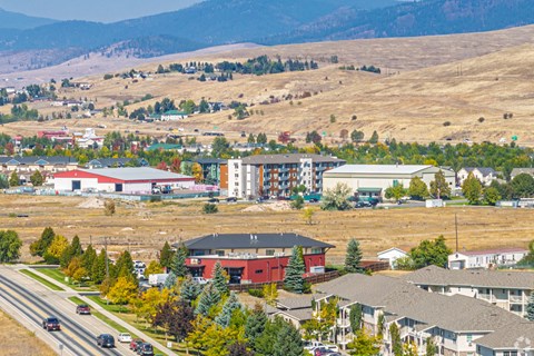 A road with cars and buildings in front of a mountain.