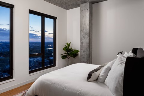 A bedroom with a large bed and a view of the city through the window.