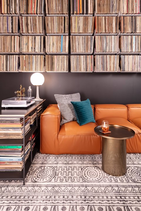 A living room with a leather couch, a table with a candle, and a wall of records.