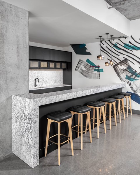A kitchen with a marble counter and bar stools.