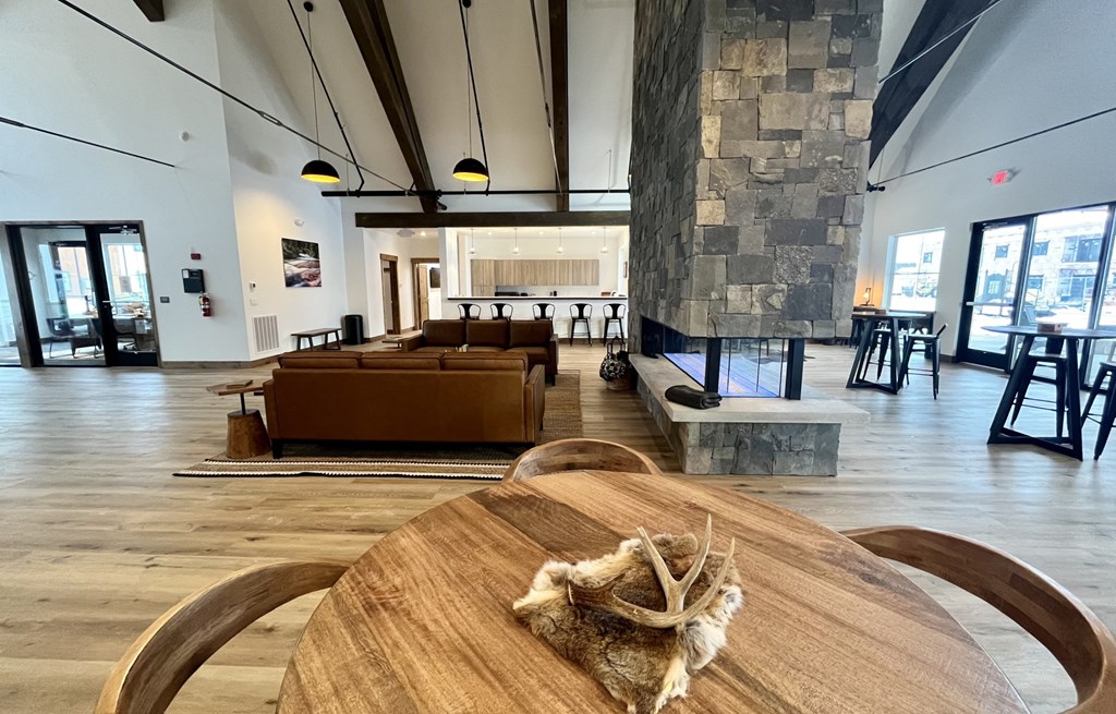 A wooden table with a cloth on it is in the foreground of an indoor space with a stone wall and wooden floors. A wooden table with a cloth on it is in the foreground of an indoor space with a stone wall and wooden floors at Silverbrook Apartments Apartments, Ridgeland, Kalispell