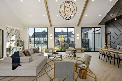 A modern living room with a grey sofa and wooden chairs.