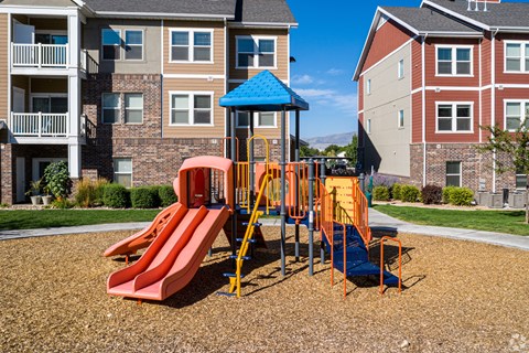 A playground with a red slide and a blue roof at The Alloy at Geneva, Vineyard, 84058