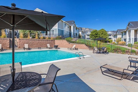 A pool area with a table and chairs and umbrella.
