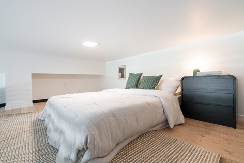 A bedroom with a bed and a nightstand.