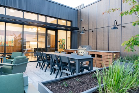 A modern outdoor dining area with a table and chairs.
