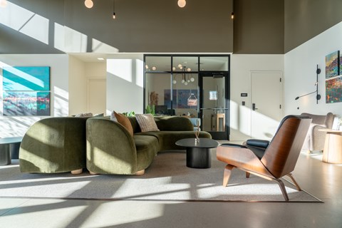 A modern living room with a green sofa and a wooden chair.