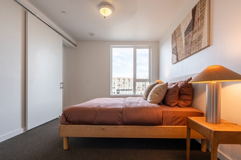 A bedroom with a bed, nightstand, and window.