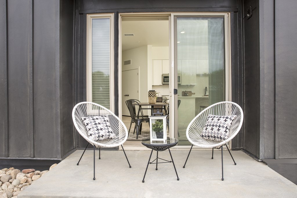 a patio with two chairs and a table and a sliding glass door