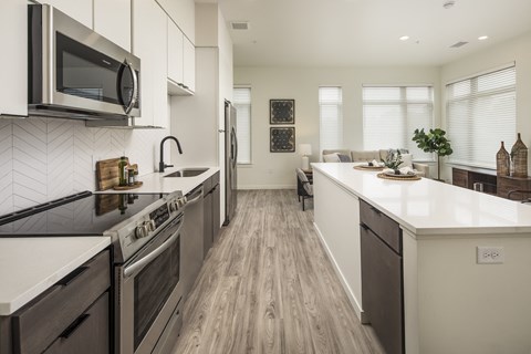 an open kitchen and living room with a large island and a stove and a microwave