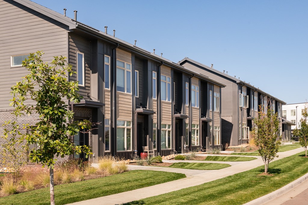 a row of townhomes with a sidewalk and grass