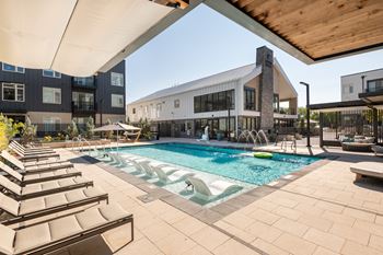 a swimming pool with lounge chairs and a building in the background