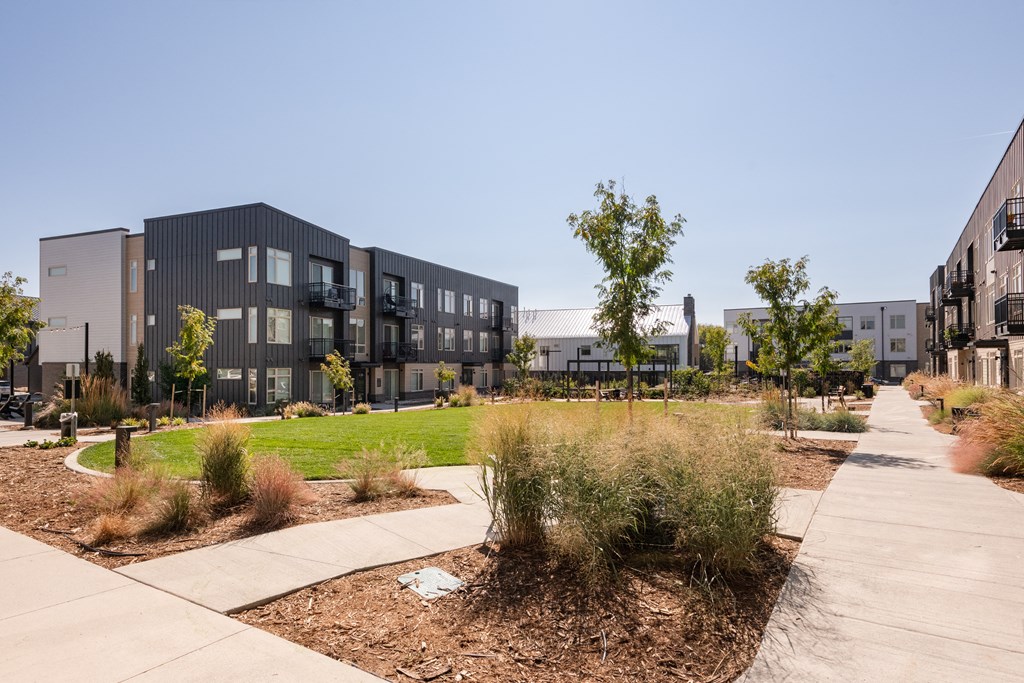 an exterior view of an apartment complex with a sidewalk and landscaping