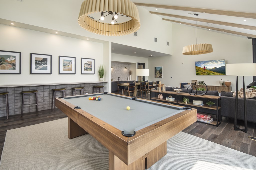 a billiards table in a clubhouse with couches and a tv