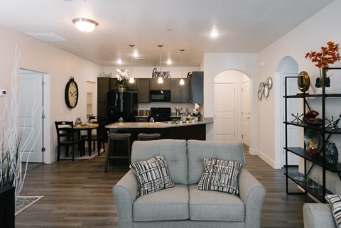 A grey couch with a striped pillow is in the middle of a kitchen and dining room.