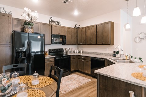 A kitchen with a table set for two and a refrigerator.