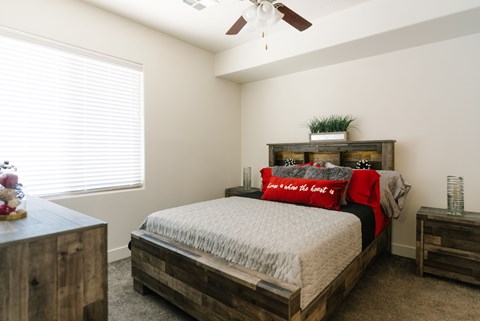 A bedroom with a bed, nightstand, and a ceiling fan.