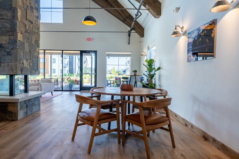 A wooden table with chairs is in the middle of a room with a stone pillar and a fireplace. at Silverbrook Apartments, Kalispell, Montana
