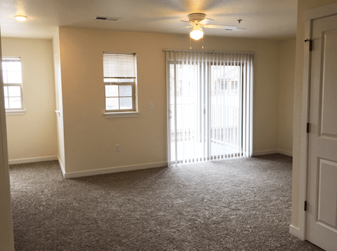 A room with a carpeted floor and a ceiling fan.