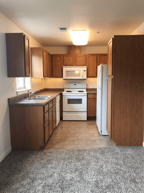 A kitchen with white appliances and wooden cabinets.