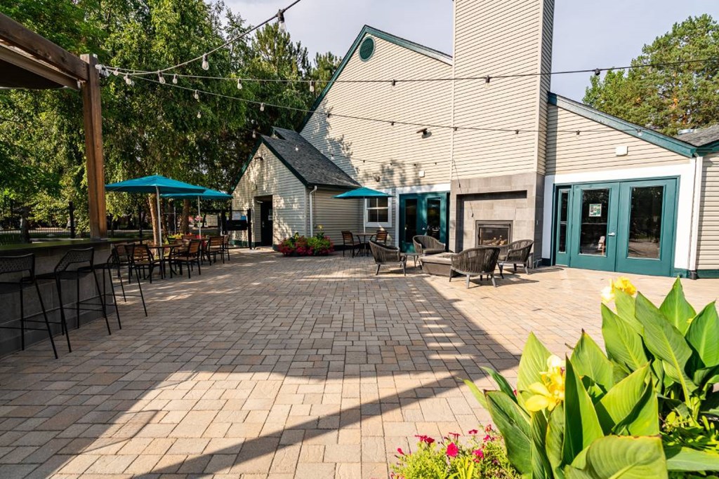 A patio area with tables and chairs is surrounded by greenery.