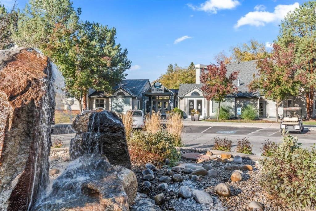 A small waterfall in front of a building surrounded by rocks and trees.